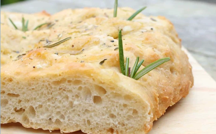 Klassieke Italiaanse focaccia met olijfolie en rozemarijn op een ambachtelijke snijplank Kelvni Itlian Artisan